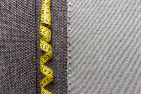 Sewing background with textured fabric and yellow measuring tape.の写真素材