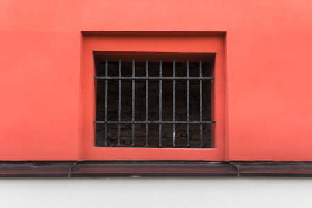 Metallic black lattice grid in the wall leading into basement for air conditioning painted in red color.の写真素材