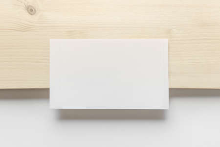 Mockup template with blank photo card on wooden and white paper background.