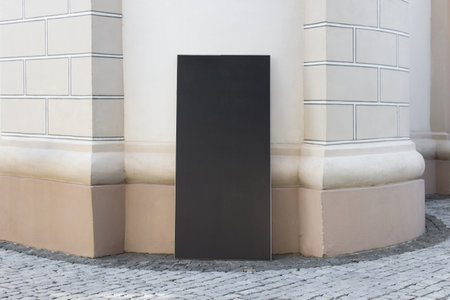 Mockup template of empty blank vertical dark brown panel information board next to historical building.の写真素材