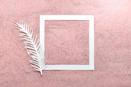 Mockup template with white paper square and white feather on real sand colored with pink color.の写真素材