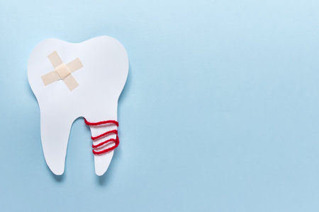 Simple concept with one damaged paper tooth with medical patch on blue background. Photo with copy...