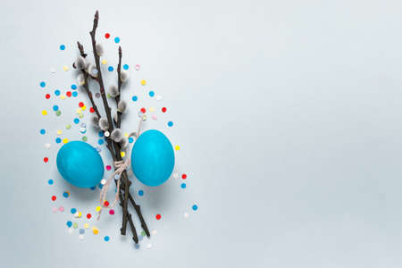 Simple minimalistic Easter composition with pussy willow branches, two colored blue eggs and colorful confetti. Photo with copy blank space.の写真素材