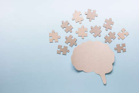 Thinking solving problems concept with many puzzle pieces and paper brain outline on blue...