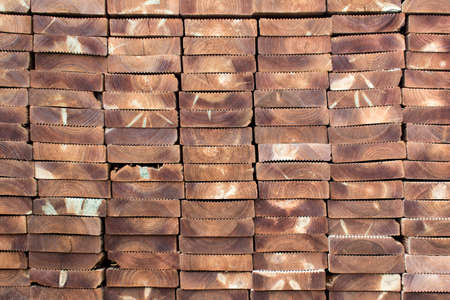 Stacks rows of brown wooden planks with uneven texture.