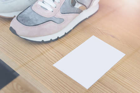Mockup template with white blank card laying on wooden shelf with sport shoe on shop stand.の写真素材