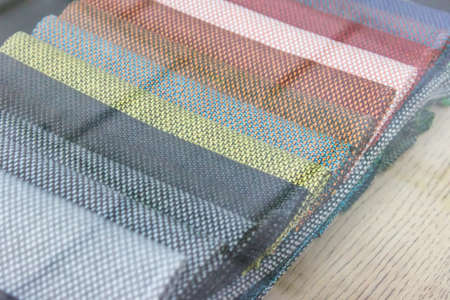 Exposition of fabric examples in many colors seen through shop window.