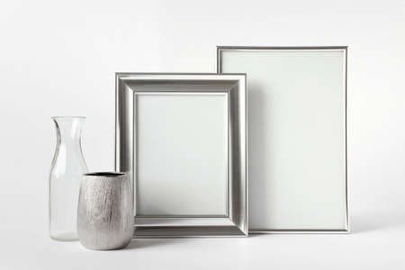 Mockup template with two blank silver frames, silver and glass small vases on white background.の写真素材