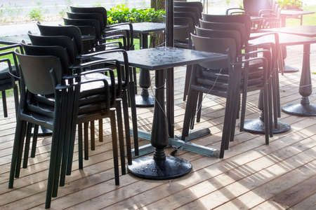 Outside summer cafe standing stacked chairs and table covered with rain drops.の写真素材