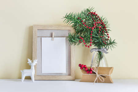 Christmas, New Year frame mockup template with Christmas decor gift, white reindeer, fir evergreen branch in glass vase.の写真素材