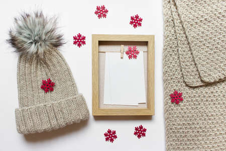 Christmas mockup template with knitted hat and scarf, wooden frame and many red wooden snowflakes.の写真素材