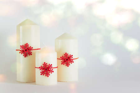 Christmas, New Year composition with three white candles and red wooden snowflakes on white background. Photo with copy blank space.の写真素材