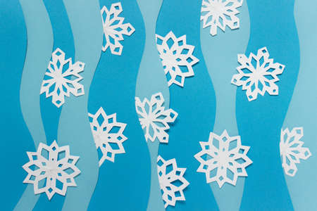 Christmas handmade paper composition with many white paper snowflakes and blue paper layers.の写真素材