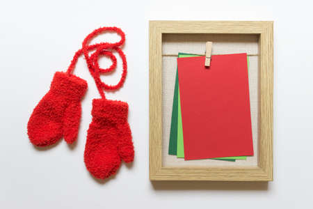 Christmas, New Year mockup, template with wooden frame and colored cards with red small kids children mittens on white background.の写真素材