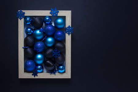 Christmas, New Year composition with many blue, dark small baubles on black backgound. Photo with copy blank space.の写真素材