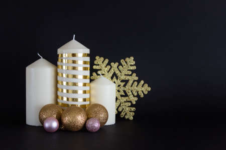Christmas, New Year composition with three candles with golden baubles and golden snowflake on black background.の写真素材