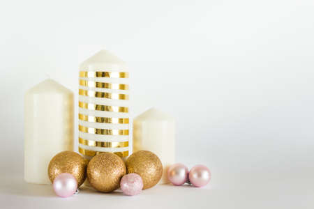Christmas, New Year composition with white candles, golden and pink baubles, balls on white backgound. Photo with copy blank space.の写真素材