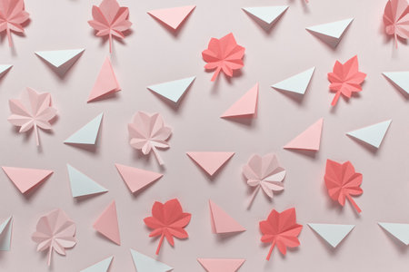 Simple background with folded origami triangles and white maple leaves in pink color.
