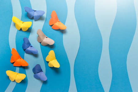 Paper composition with colorful origami butterflies on blue wavy background.の写真素材