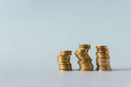 Three stacks of yellow coins on blue background. Image with copy blank space.の写真素材