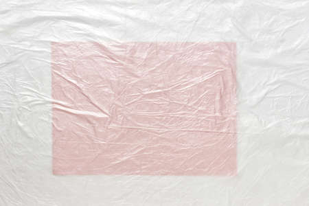Large A4 blank empty pink paper sheet covered with white plastic cellophane foil with wrinkles.