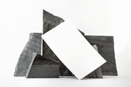 Mockup template with blank card next to composition of black raw natural stones on white background.の写真素材