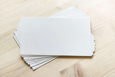 Mockup template with many white cards stacked and rotated on light wooden surface.