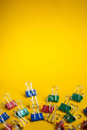 Colorful background with office supplies. Paper clips on a bright yellow background. The concept of a new school year at school. Abstract background from bright paper clips. Office toolsの写真素材