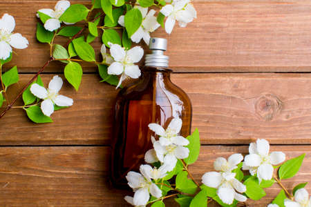 Perfume. Essential oil. Dark glass jar. Natural cosmetic. Natural perfume. Floral background. Flat lay. Bottle with fragrant water. On a wooden background. The concept of healthy natural cosmetics.の写真素材