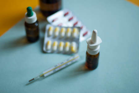 Medicines for colds, flu, viral diseases. Cough and cold remedies. Glass jars with syrup, colored tablets. Pills on a blue background. Antiviral drugs.の写真素材