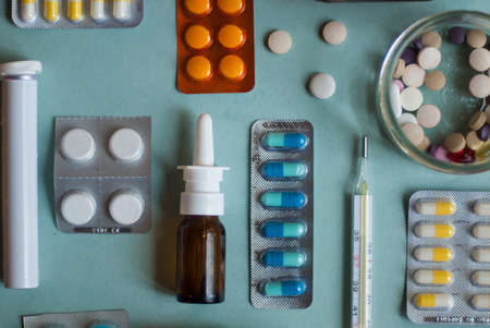 Medicines for colds, flu, viral diseases. Cough and cold remedies. Glass jars with syrup, colored tablets. Pills on a blue background. Antiviral drugs.の写真素材