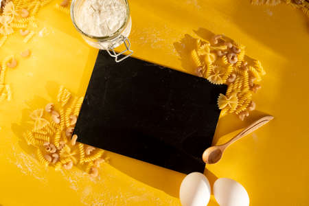 Assorted Italian pasta. On a yellow background. View from above. Pasta on a plate. Flour, eggs and...