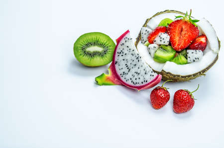 Pieces of strawberries, kiwi and dragon fruit in a half of coconut. 2 berries of strawberries, half kiwi and a slice of dragon fruit.の写真素材