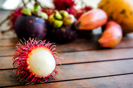 Half-peeled rambutan on the background of different fruits on the table.の写真素材