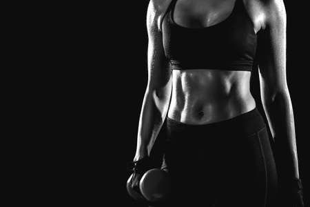 Black and white photo of a girl holding a dumbbell in her hand.の写真素材