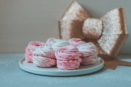 Plate with home made zephyr sweets with glittery bow on the backgroundの写真素材