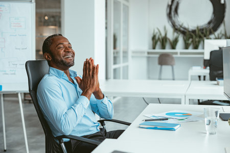 Handsome african businessman working computer while sitting in modern coworkingの写真素材