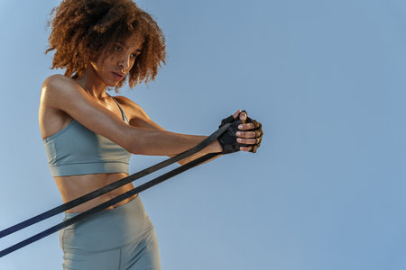 Sporty woman performs exercises for muscles of hands use expander on studio background