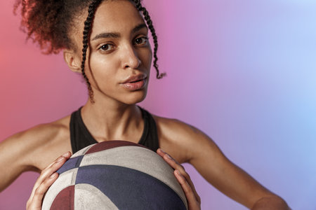 Close up of woman basketball player in sportswear holding ball while standing on studio backgroundの写真素材