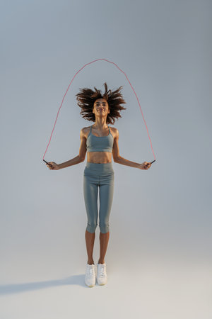 Woman skipping with jump rope on studio background. Strength and motivation. Best cardio workoutの写真素材