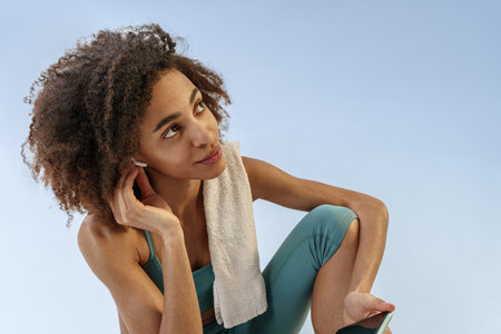Close up of woman in headphones resting after training and listening music on studio background