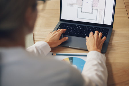 Close up of woman architect creating new project on laptop while sit on the office deskの写真素材