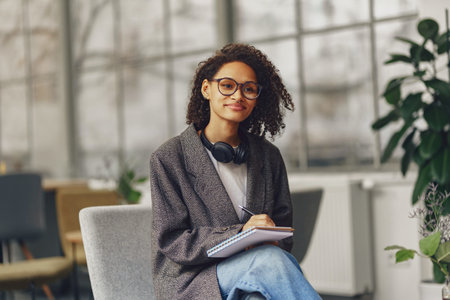 Young woman student in headphones making notes in a notebook in the modern coworkingの写真素材