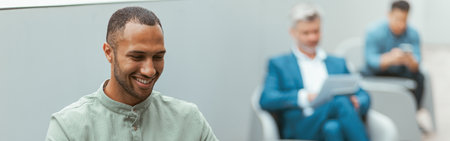 Handsome african businessman working on laptop sitting in coworking on colleagues backgroundの写真素材