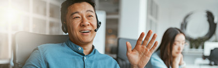 Smiling asian businessman talking phone with client while sitting in office on colleague backgroundの写真素材