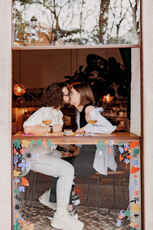 Couple in love kissing during date while sitting in bar and drinking wineの写真素材