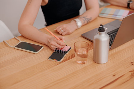 Close up of woman freelancer making notes during work in cozy coworkingの写真素材