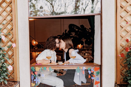 Couple in love kissing during date while sitting in bar and drinking wineの写真素材