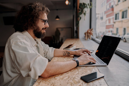 Smiling male freelancer working on laptop while sitting in modern coworking. Remote work concept