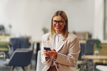 Stylish businesswoman carries out business correspondence on the phone standing in coworkingの写真素材